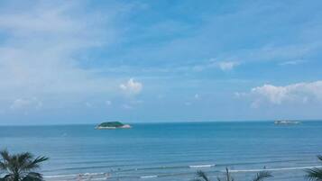 Ein Strand mit blauem Himmel, ruhigem Wasser und fernen Inseln.