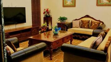 Una sala de estar con sofá, mesa de centro, televisor y plantas decorativas.