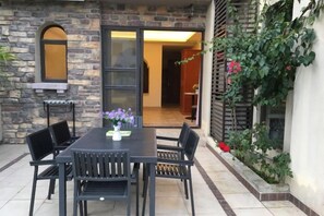 An outdoor patio with a table and chairs, a stone wall, and a sliding glass door leading to an interior space. - Shuangyue Bay Vanke Scenic Apartment Villa Guesthouse (Huidong)