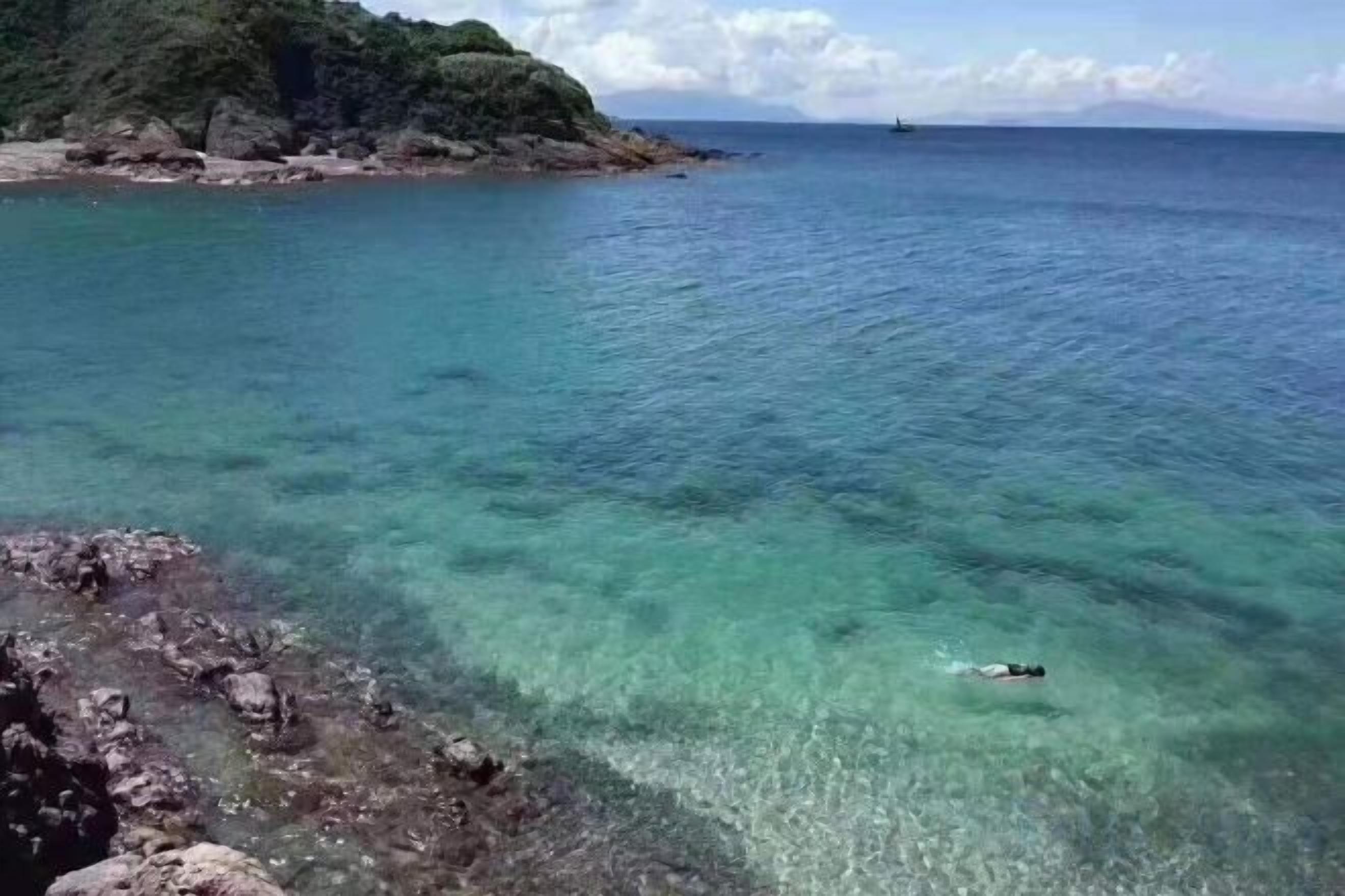 Una vista despejada del litoral con una persona nadando en el agua.