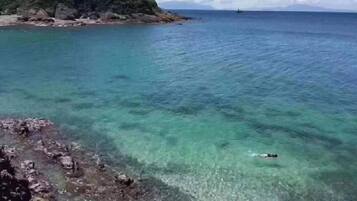 Una vista despejada del litoral con una persona nadando en el agua.