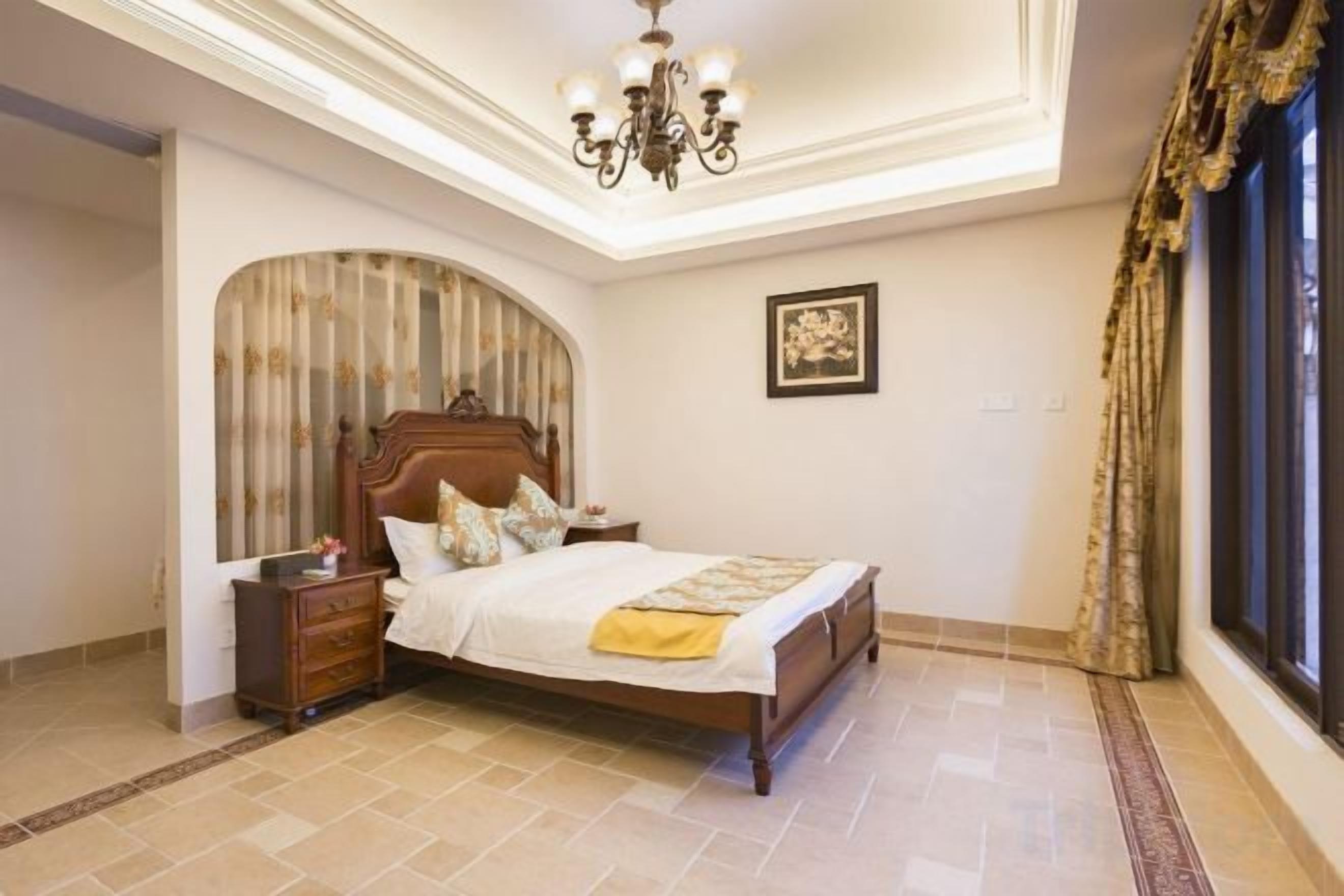 A bedroom with a bed, nightstand, and a chandelier.