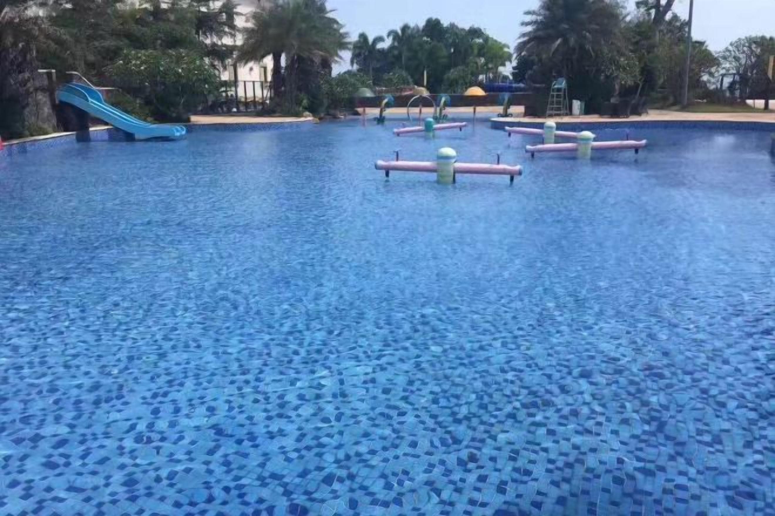 A swimming pool with a blue tiled floor and a blue slide.