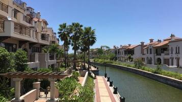 A canal with buildings on either side, a clear sky, and a pergola with seating.