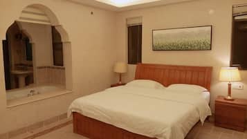 A bedroom with a bed, a nightstand, a lamp, a painting, and a mirror.