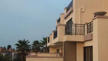 A multi-story residential building with balconies, a flat roof, and a beige exterior.
