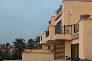 Un edificio residencial de varios pisos con balcones, techo plano y fachada color beige.