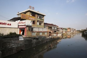 A riverside building with multiple floors, a visible restaurant sign, and a reflection in the water. - Shanghai Xiangyi Hotel (Shanghai)