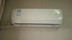 Un aire acondicionado blanco, fijado a la pared, con panel de control y cable de alimentación.