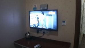 Un televisor montado en la pared con un control remoto sobre una mesa.