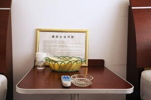 A table with a framed sign, a basket, a cup, and a remote control. - Shanghai Xiangyi Hotel (Shanghai)