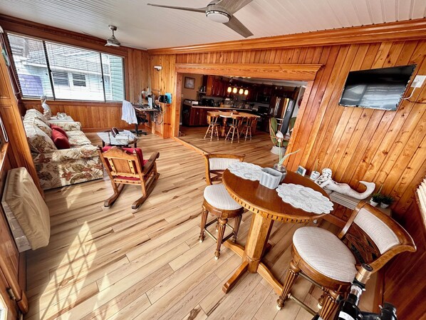 A wooden-floored living room with a sofa, rocking chair, and dining table.