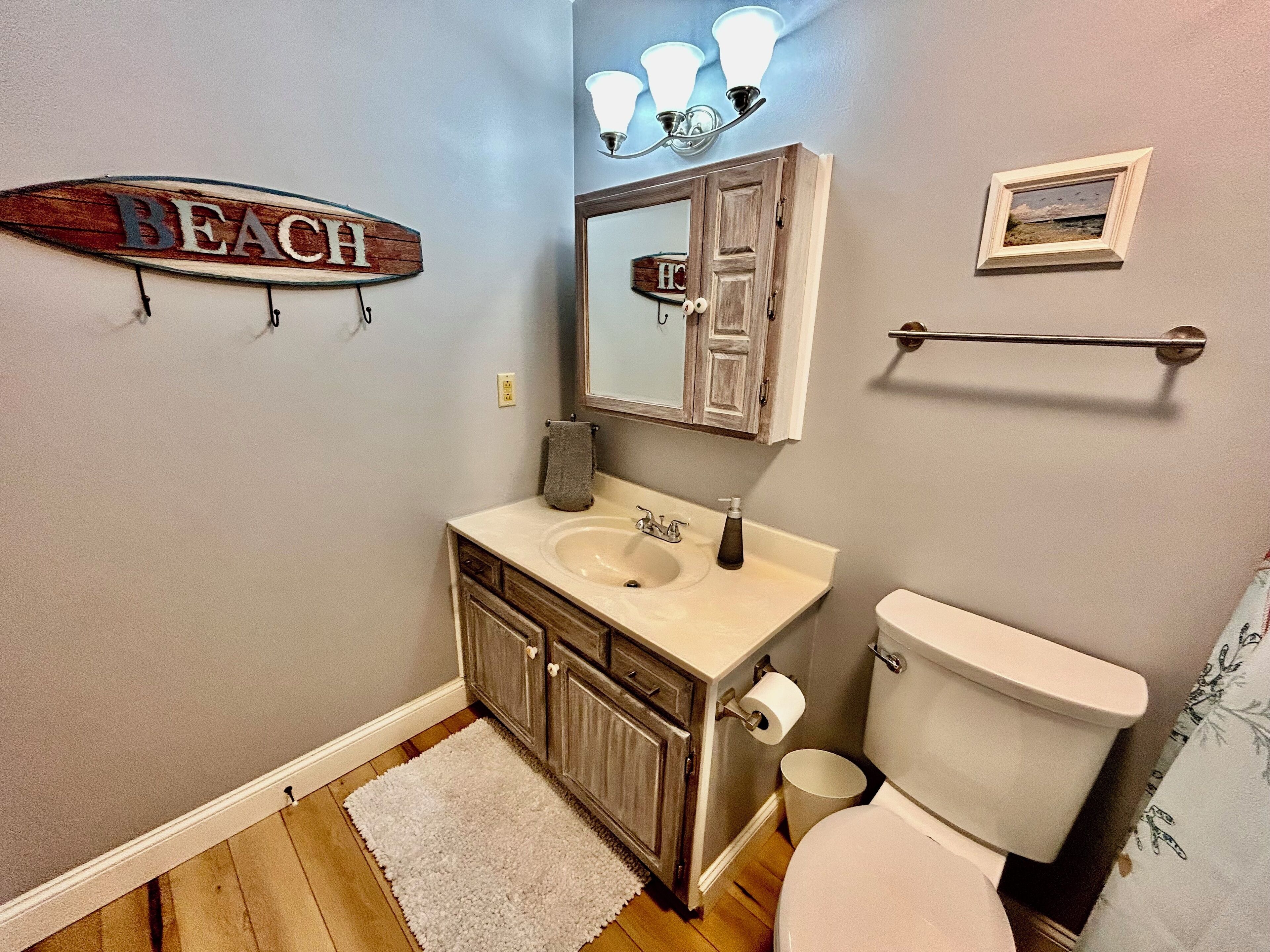 Une salle de bain avec un meuble-lavabo en bois, un évier, des toilettes et un porte-serviettes.