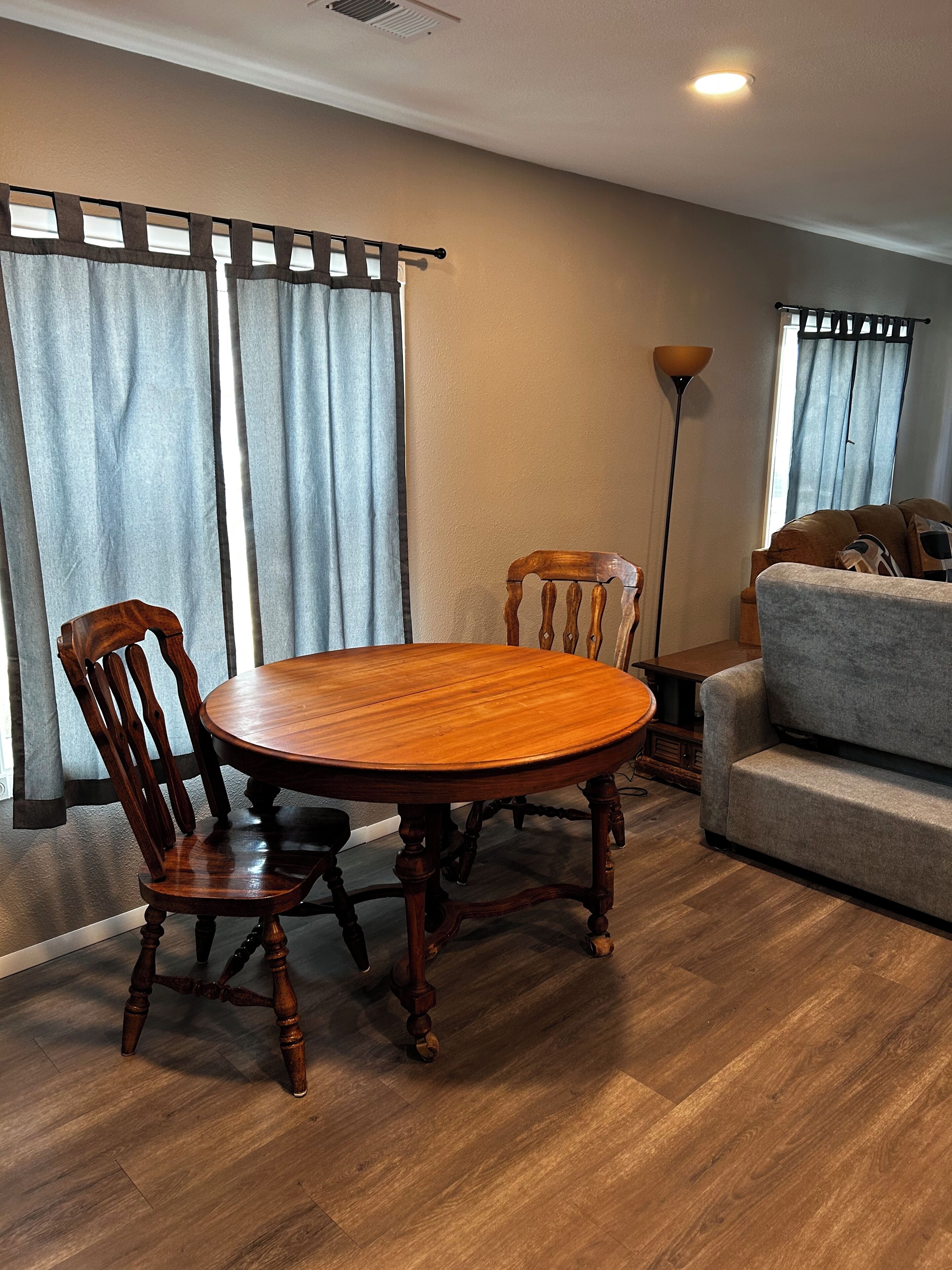 Un coin repas avec une table et des chaises en bois, un canapé et une lampe sur pied.