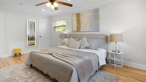 A bedroom with a bed, bedside tables, a ceiling fan, a window, and a door. - 5BR Indianapolis Fun Home Arcade games & Gameroom (Indianapolis)