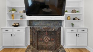 A living room with a fireplace, white cabinetry, and a flat-screen TV. - 5BR Indianapolis Fun Home Arcade games & Gameroom (Indianapolis)