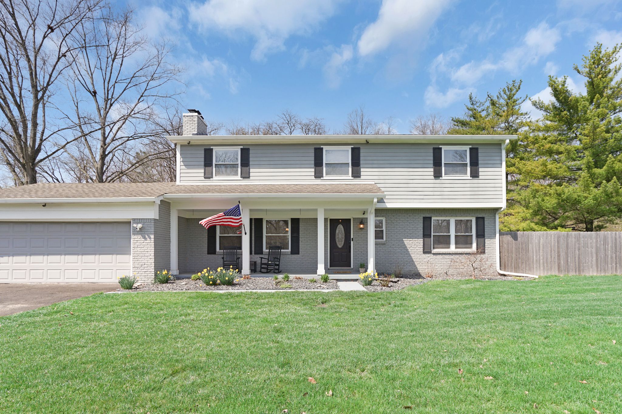 A two-story house with a front porch, a garage, and a well-maintained lawn.