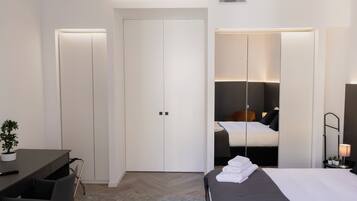 Ein modernes Hotelzimmer mit Bett, Nachttisch, Lampe und Schreibtisch mit Stuhl.