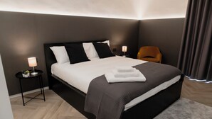 A modern bedroom with a large bed, a bedside table with a lamp, and a chair.