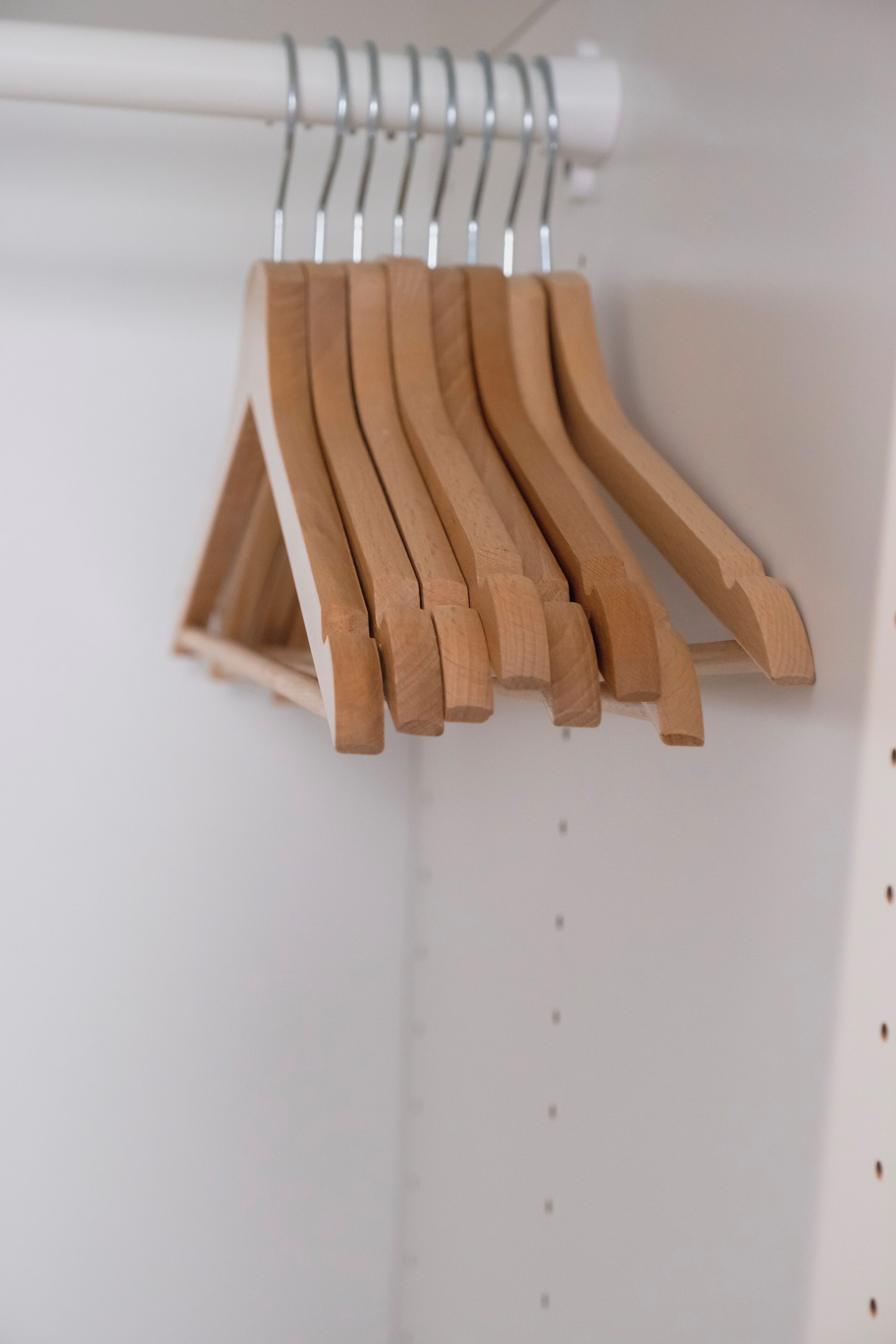Un portabiti in metallo bianco con grucce di legno.