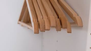 Un portabiti in metallo bianco con grucce di legno.