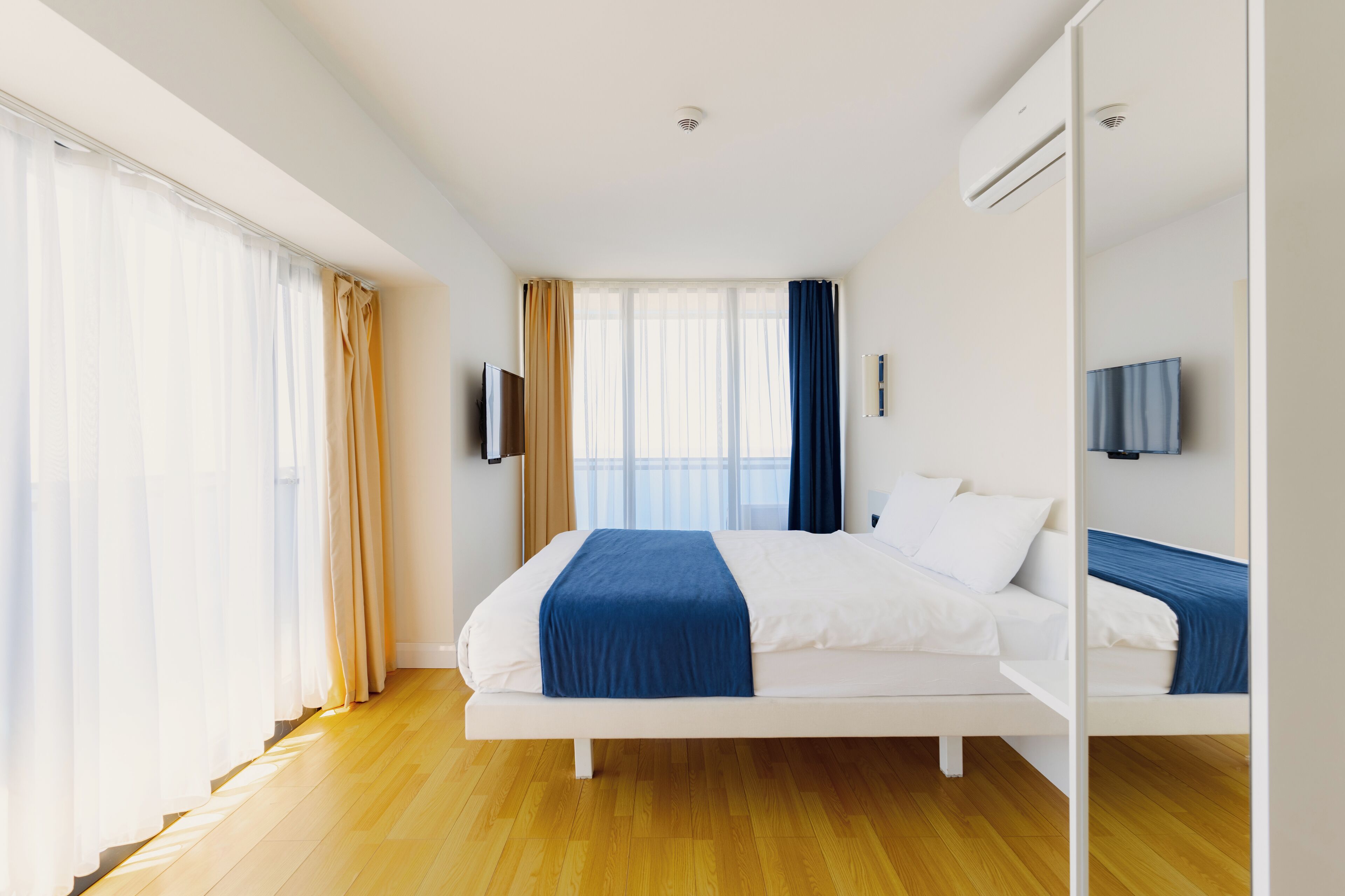 Une chambre d’hôtel moderne dotée d’un grand lit, d’un téléviseur à écran plat et d’une grande fenêtre avec des rideaux.