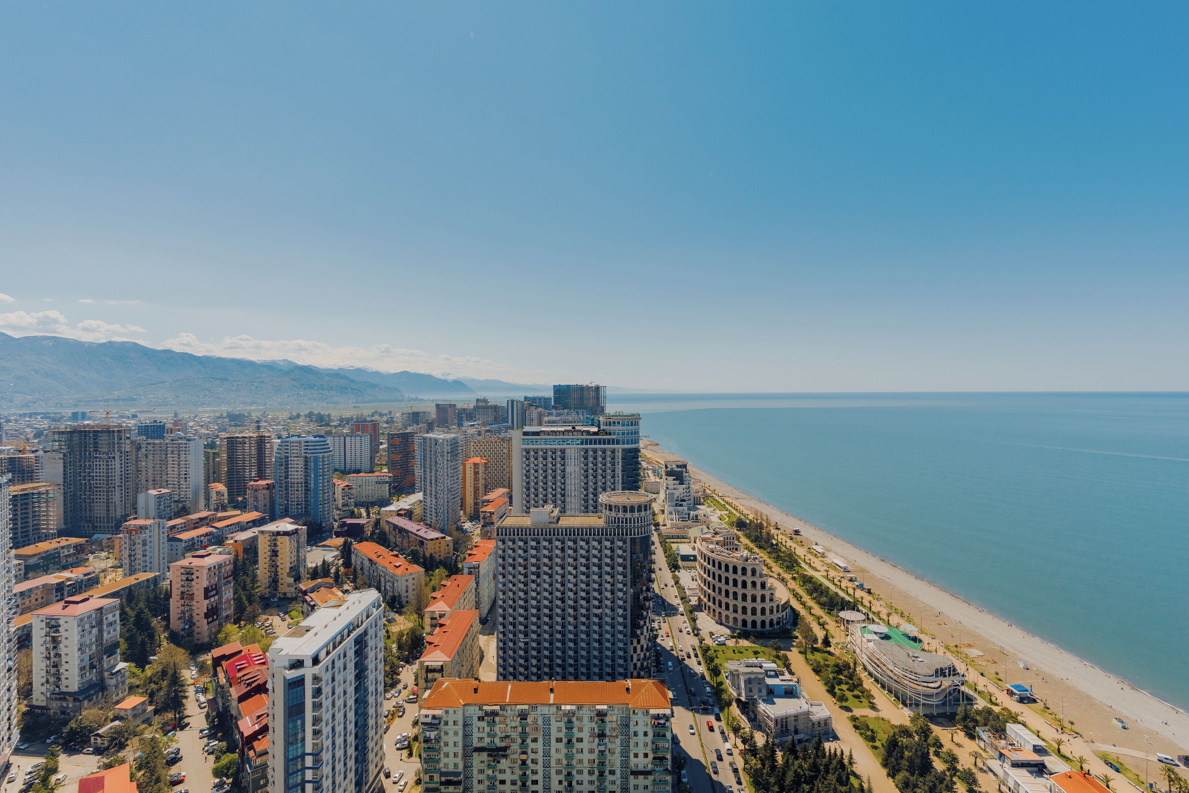 A coastal cityscape with high-rise buildings, a beach, and a clear view of the sea.