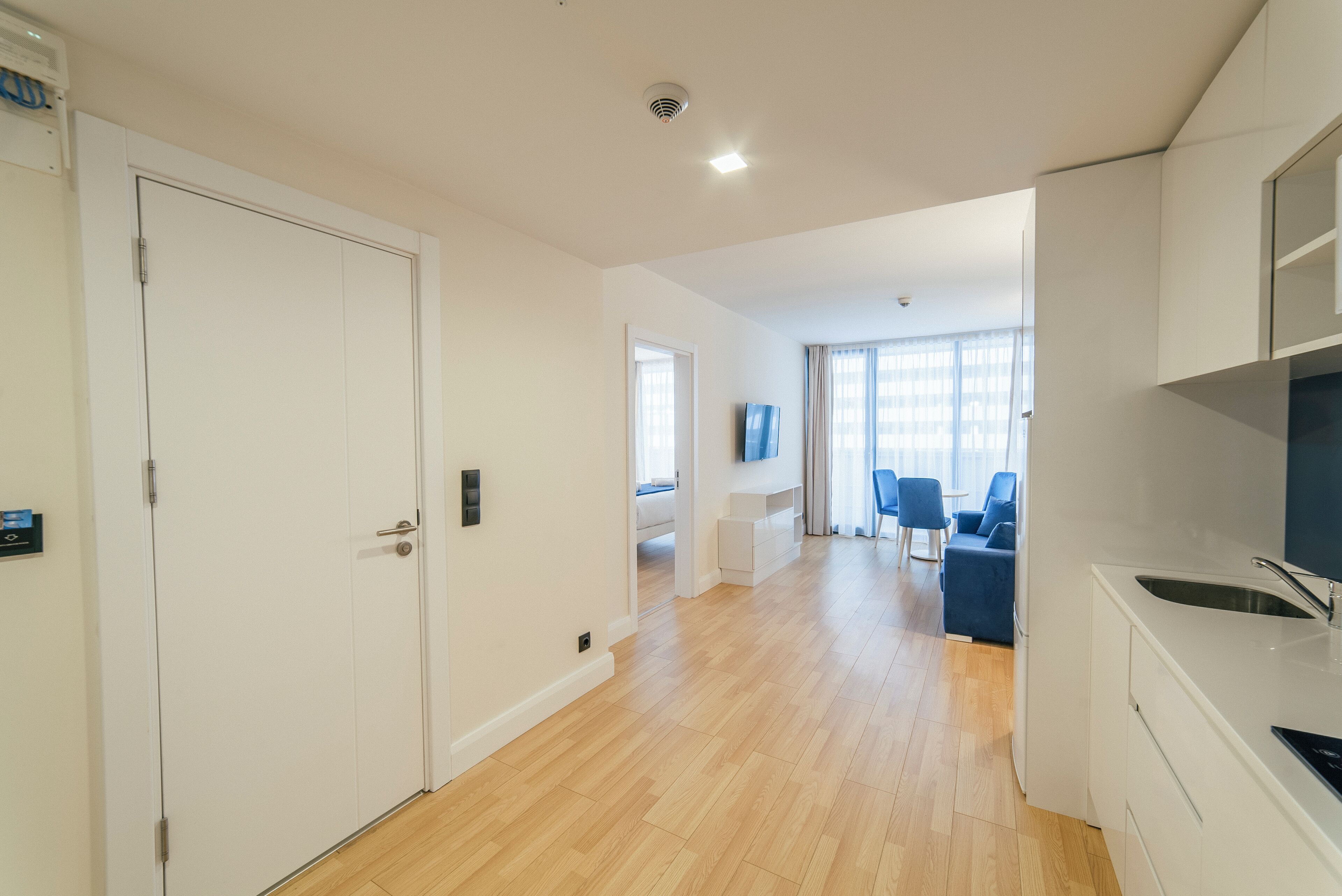 A modern apartment with a kitchen, dining area, and a living room with a TV.