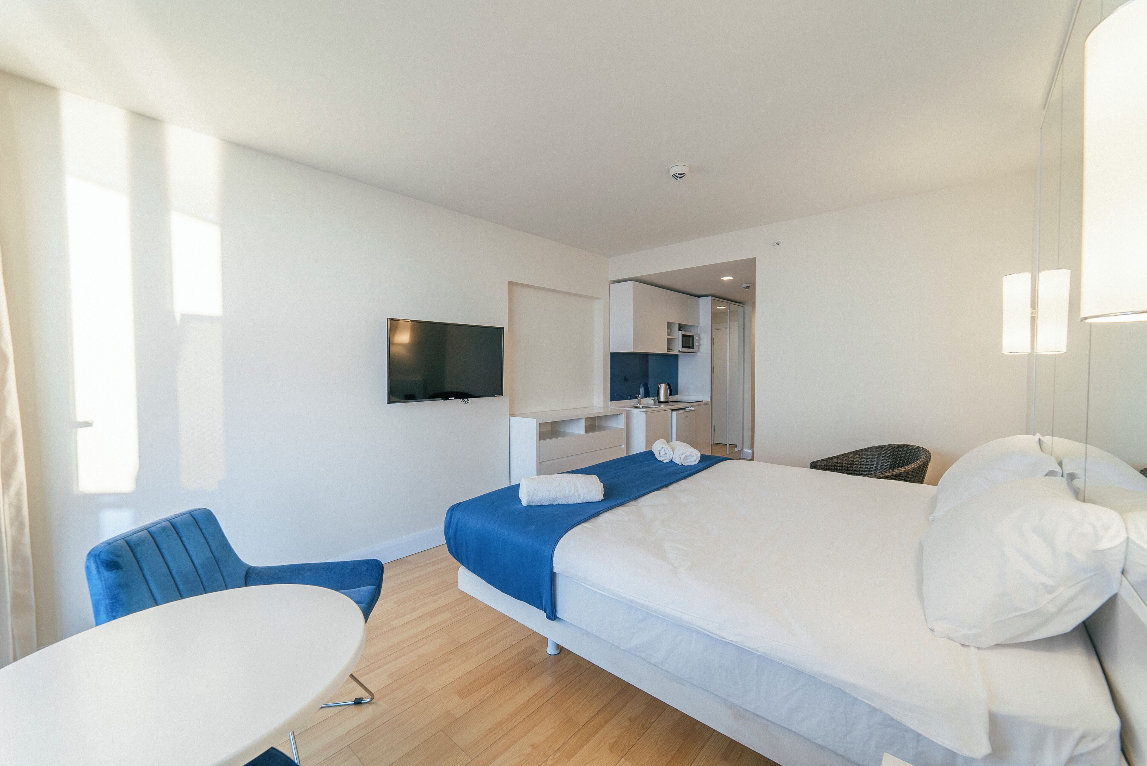 A modern hotel room with a bed, a desk, and a television.