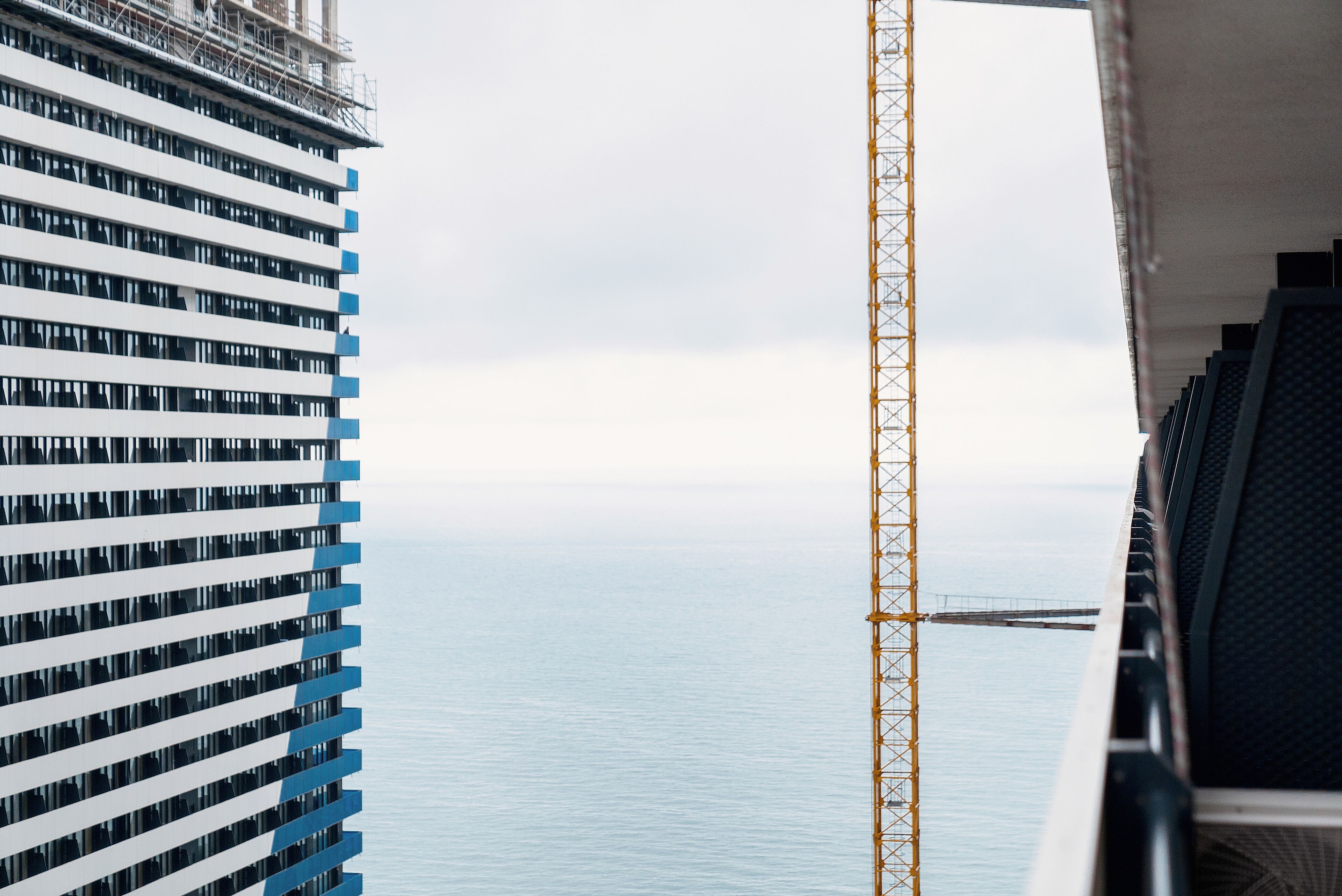 Un immeuble de grande hauteur offrant une vue sur la mer, avec une grue de construction à proximité.