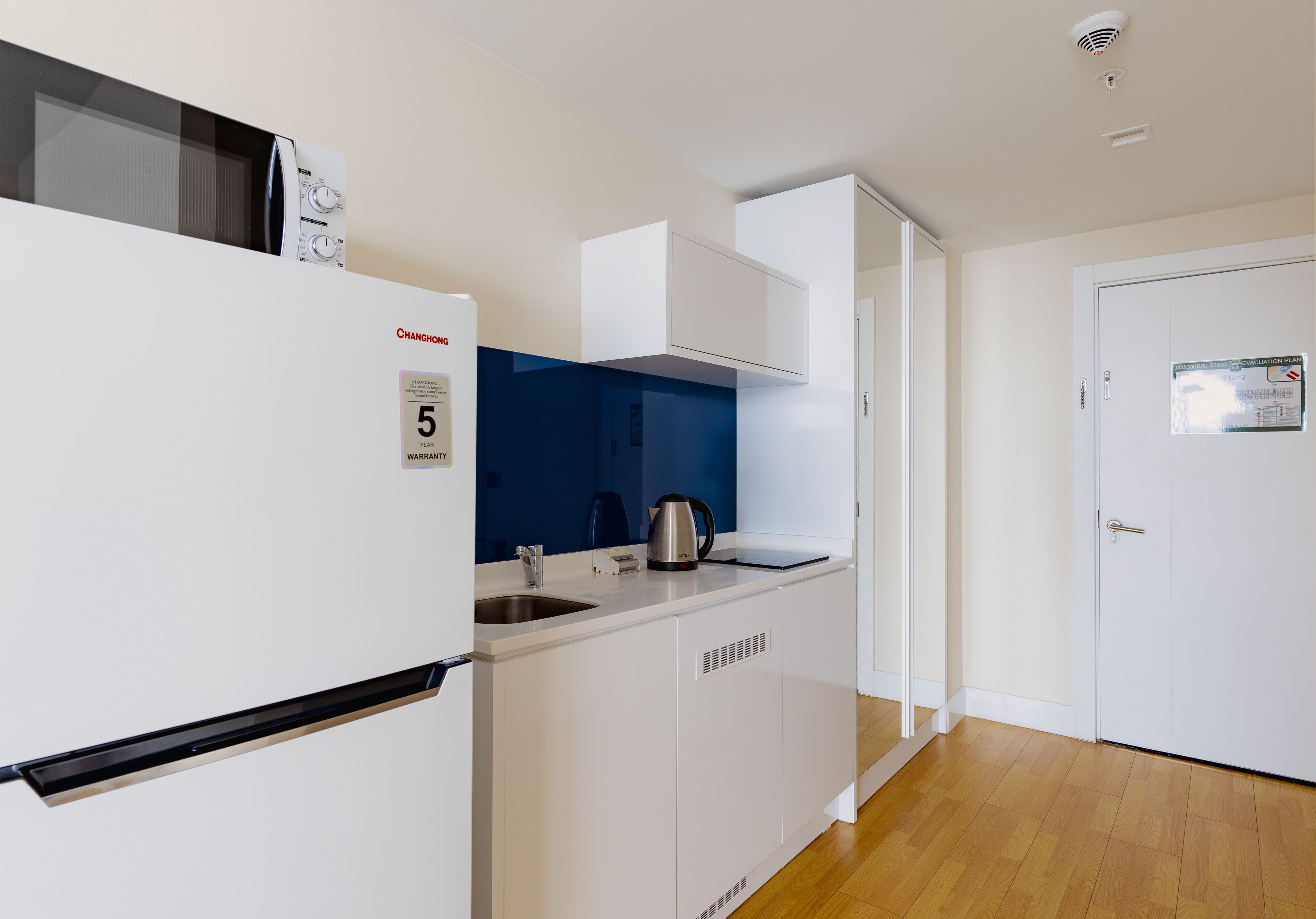 Eine kleine Küche mit integriertem Kühlschrank, Wasserkocher und Spüle.