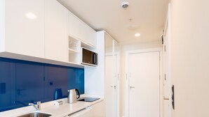 Een moderne keuken met witte kasten, een roestvrijstalen spoelbak, een waterkoker en een magnetron.