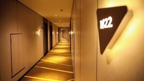 A hotel corridor with a carpeted floor, a wall-mounted sign displaying the number 122, and a door on the left. - IU Hotel (Chongqing Nanping Wanda Plaza Light Rail Station) (Chongqing)