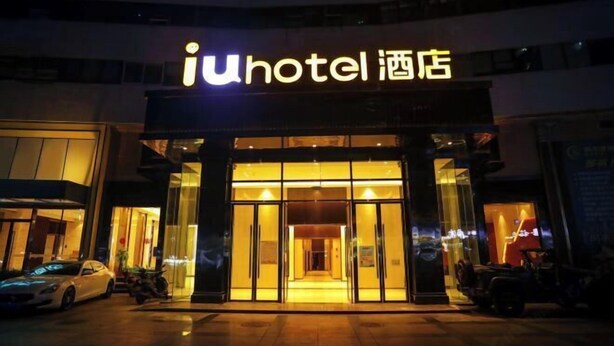 A hotel entrance with a glass facade and illuminated signage. - IU Hotel (Chongqing Nanping Wanda Plaza Light Rail Station) (Chongqing)