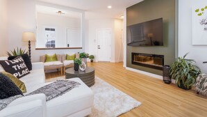 A modern living room with a white sofa, a round coffee table, and a fireplace.