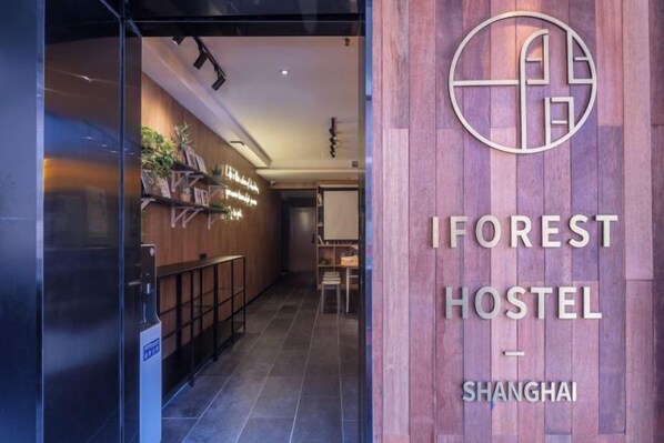 The entrance to IFOREST HOSTEL in Shanghai with a wooden facade and a clear view of the interior.