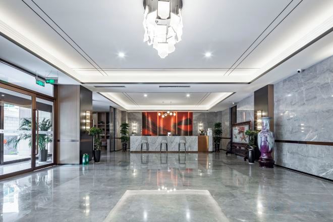 Un vestíbulo de hotel con una recepción, zona de estar y un espejo grande.
