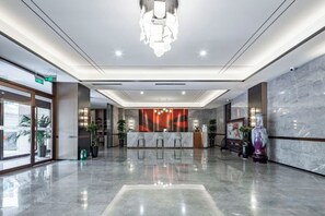A hotel lobby with a reception desk, seating area, and a large mirror. - Zhengzhou Xinyang Lingrui Building Hotel (Provincial People's Hospital Metro Station) (Zhengzhou)