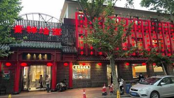 A traditional Chinese building with a red and black facade, a signboard with Chinese characters, and a visible entrance.