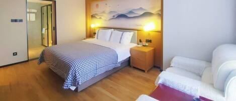 A hotel room with a bed, bedside table, lamp, and a painting on the wall.