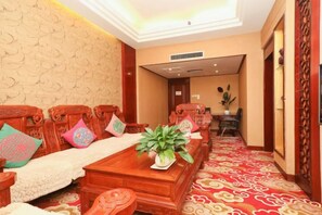 Una habitación tradicional con una larga mesa de madera, sillas con cojines y una alfombra estampada.