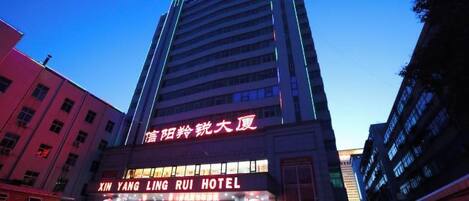 A multi-story hotel building with signage for 'XIN YANG LING RUI HOTEL' and 'XIN YANG LING RUI HOTEL' in large letters.