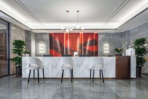 A reception area with a marble counter, three chairs, and two potted plants. - Zhengzhou Xinyang Lingrui Building Hotel (Provincial People's Hospital Metro Station) (Zhengzhou)