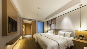 Une chambre d’hôtel moderne dotée d’un grand lit, de tables de chevet, d’un téléviseur à écran plat fixé au mur et d’un plancher en bois.