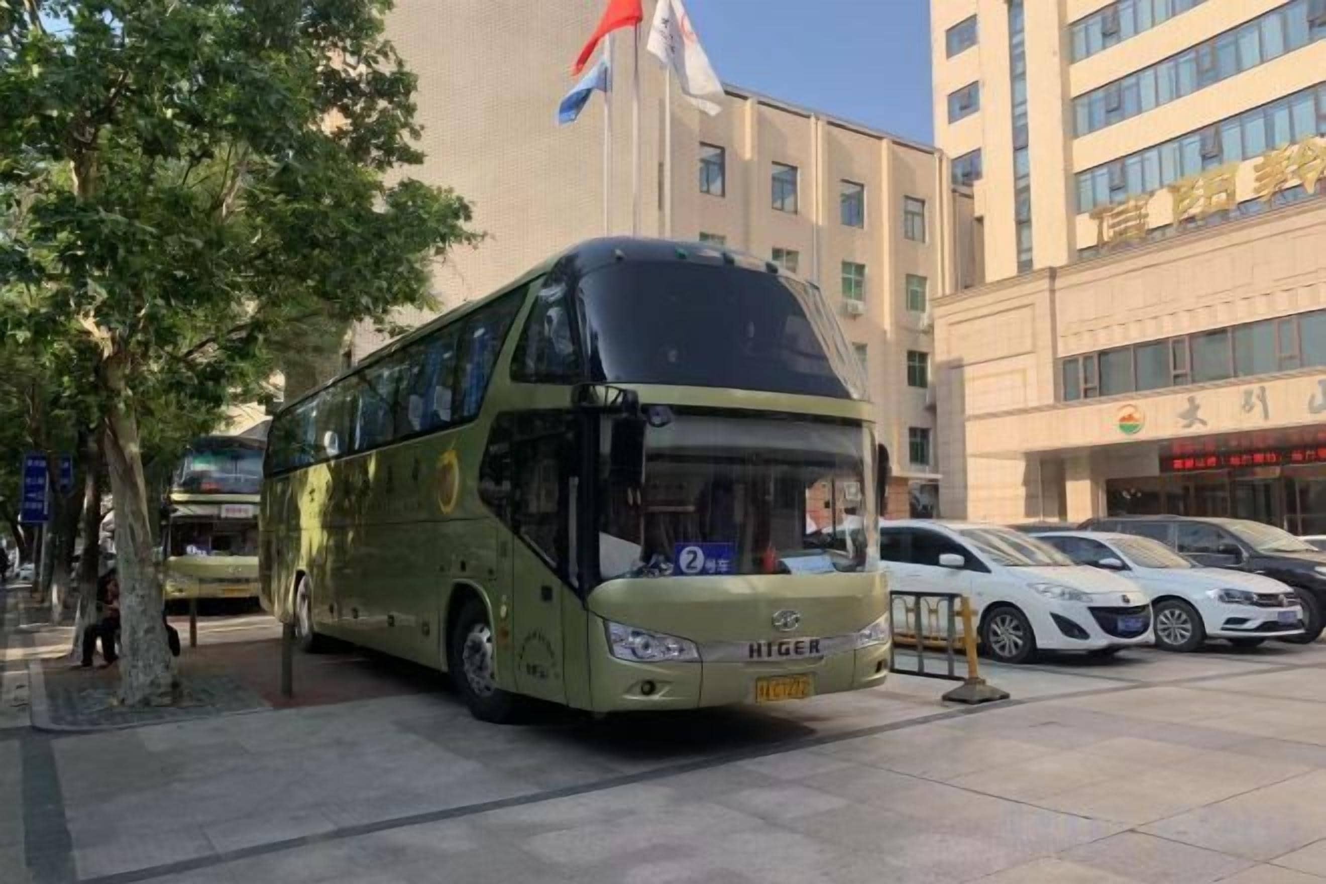 Een dubbeldekkerbus geparkeerd voor een gebouw met meerdere verdiepingen en een vlag.