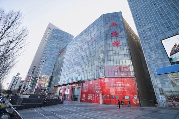 A modern building with reflective glass facades and red signage.