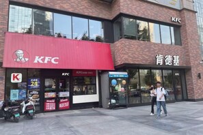 Un restaurante KFC con un toldo rojo y señalización en un idioma extranjero.