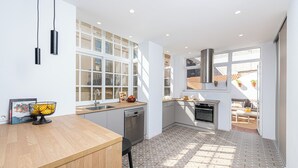 Eine moderne Küche mit einer Holz Arbeitsplatte, Edelstahlgeräten und großen Fenstern für viel Tageslicht.