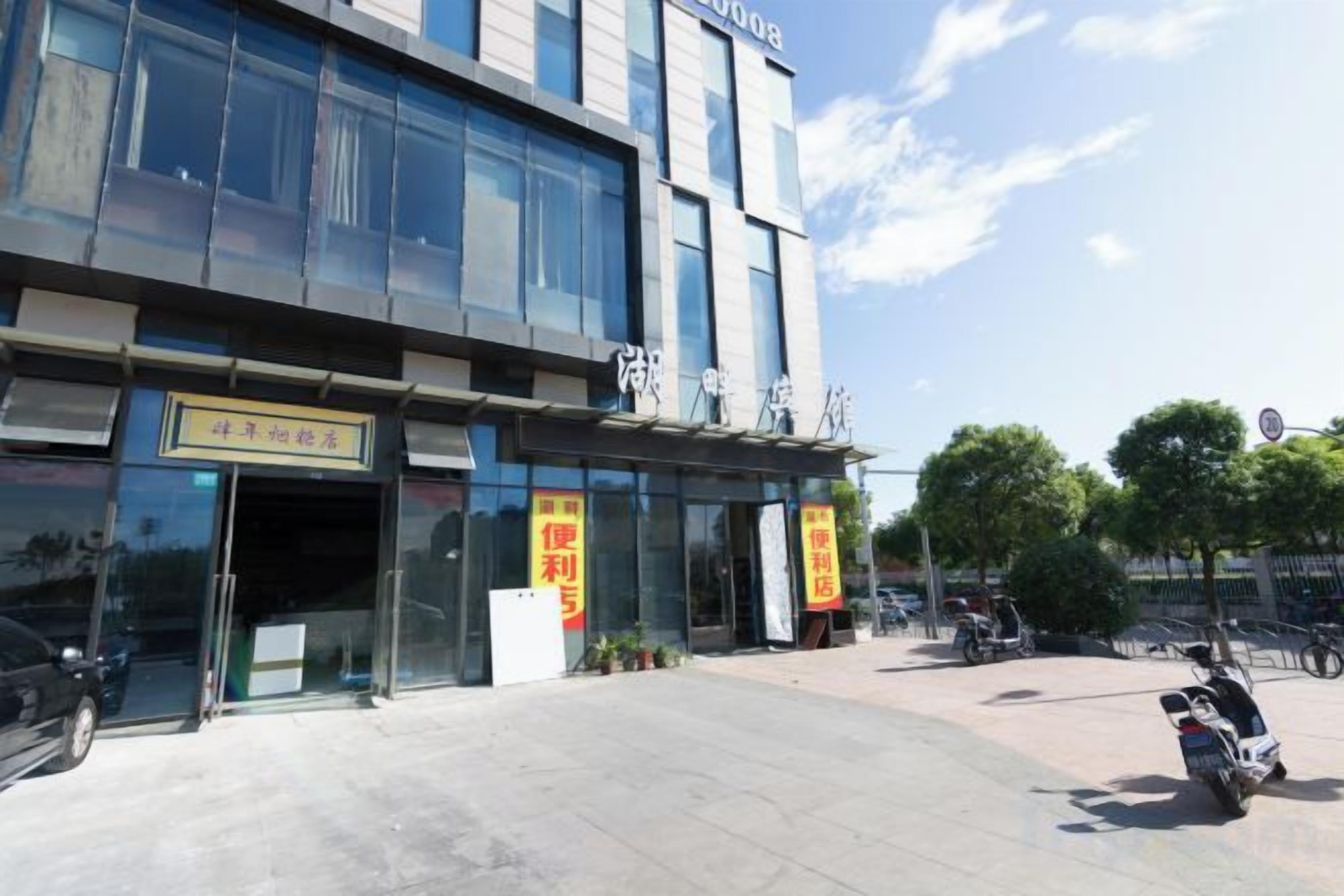 A building with a storefront, a clear sky, and a parked motorcycle.