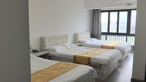 Habitación de hotel con tres camas, una ventana con vistas y aire acondicionado instalado en el techo.